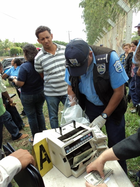 Un oficial de policia pasa vista de la maquinuta contadora de billetes